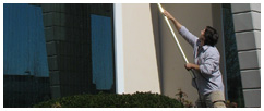 Paul Black reaching to clean window on second floor commercial building.